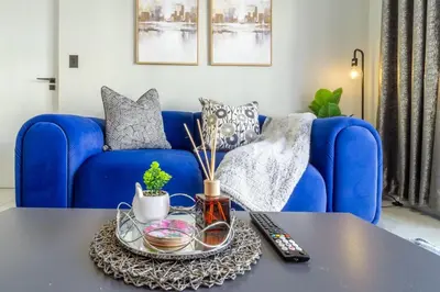 a living room with a blue couch and a table at AlimamaSpaces Phillys Whisken in Midrand