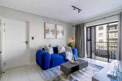 a living room with a blue couch and a window at AlimamaSpaces Phillys Whisken in Midrand