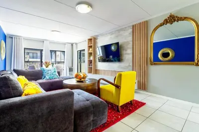 a living room with a couch and a yellow chair at AlimamaSpaces Farais Whisken Apartment in Midrand