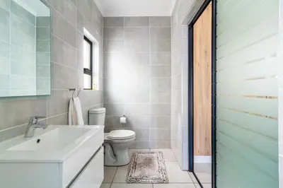 a bathroom with a white toilet and a sink at AlimamaSpaces Farais Whisken Apartment in Midrand