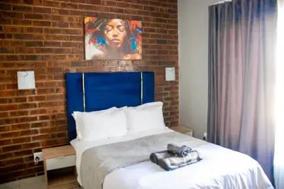 a bedroom with a large bed with a brick wall at Glowti Event & Guest House in Centurion