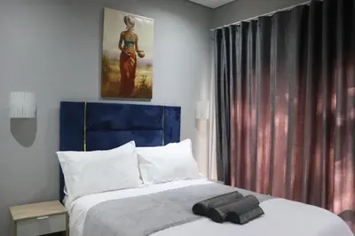 a bedroom with a bed with a blue headboard at Glowti Event & Guest House in Centurion