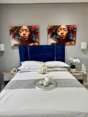 a bedroom with a bed with two paintings on the wall at Glowti Event & Guest House in Centurion