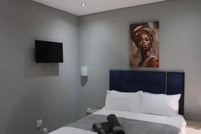 a bedroom with a bed with a painting on the wall at Glowti Event & Guest House in Centurion