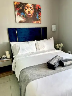 a bedroom with a large white bed with a painting on the wall at Glowti Event & Guest House in Centurion