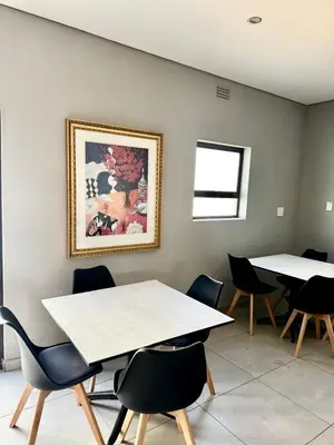 a room with two tables and chairs and a painting on the wall at Glowti Event & Guest House in Centurion