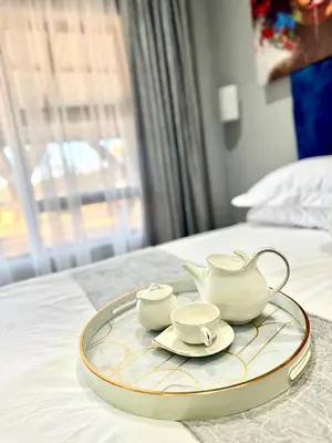 a tray with two cups and a tea set on a bed at Glowti Event & Guest House in Centurion
