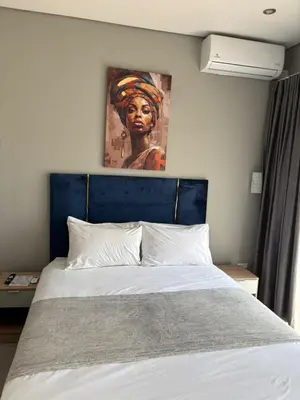 a bedroom with a bed with a painting on the wall at Glowti Event & Guest House in Centurion