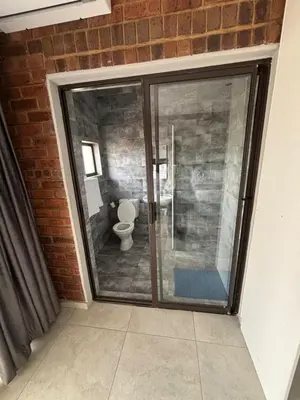 a bathroom with a glass shower and a toilet at Glowti Event & Guest House in Centurion