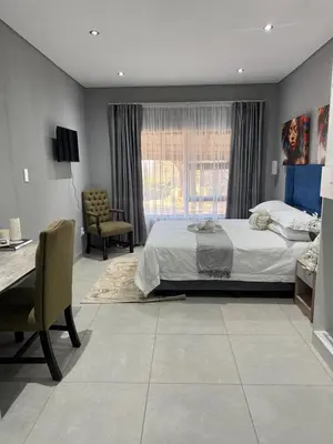 a bedroom with a large bed and a desk and a desk at Glowti Event & Guest House in Centurion