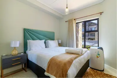 a bedroom with a bed with a green headboard and a window at #AlimamaSpaces Jay's Polofields in Midrand