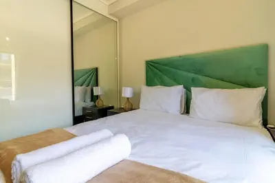 a bedroom with a white bed with a green headboard at #AlimamaSpaces Jay's Polofields in Midrand