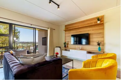 a living room with two couches and a tv at #AlimamaSpaces Jay's Polofields in Midrand