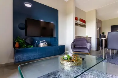 a living room with a blue wall with a tv at #AlimamaSpaces The Manson's Kyalami Woods in Midrand