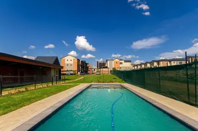 a swimming pool with a fence and some buildings at #AlimamaSpaces The Manson's Kyalami Woods in Midrand