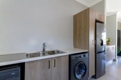 a kitchen with a sink and a washing machine at #AlimamaSpaces The Rob's Kyalami Woods in Midrand