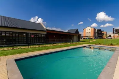 a large swimming pool in front of a building at #AlimamaSpaces The Rob's Kyalami Woods in Midrand