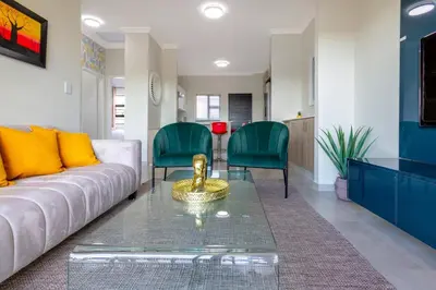 a living room with a white couch and green chairs at #AlimamaSpaces The Rob's Kyalami Woods in Midrand