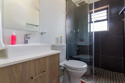 a bathroom with a toilet and a sink and a shower at #AlimamaSpaces The Rob's Kyalami Woods in Midrand