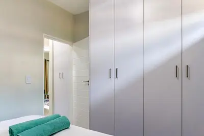 a bathroom with white cabinets and a green towel on a bed at #AlimamaSpaces The Chelsea Kyalami Woods in Midrand