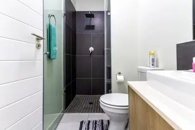 a bathroom with a toilet and a glass shower door at #AlimamaSpaces The Chelsea Kyalami Woods in Midrand