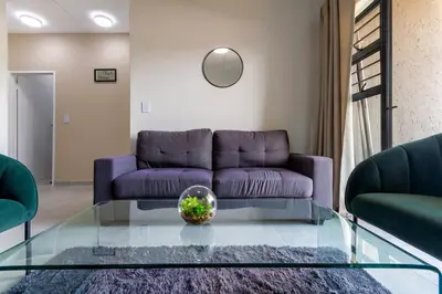 a living room with a purple couch and a glass table at #AlimamaSpaces The Chelsea Kyalami Woods in Midrand