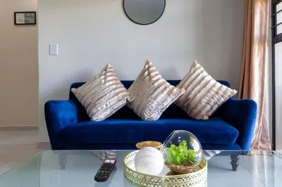 a blue couch with four pillows on it at #AlimamaSpaces The Bob's Kyalami Woods in Midrand