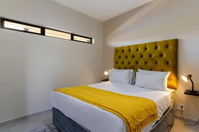 a bedroom with a large bed with a yellow blanket at #AlimamaSpaces The Bob's Kyalami Woods in Midrand