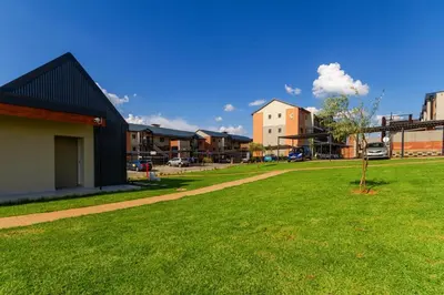 a park with a building and a tree in the grass at #AlimamaSpaces The Bob's Kyalami Woods in Midrand