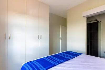 a bedroom with white cabinets and a blue bed at #AlimamaSpaces The Bob's Kyalami Woods in Midrand