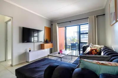 a living room with a couch and a tv at #AlimamaSpaces Thando's Waterfalls Villa in Midrand