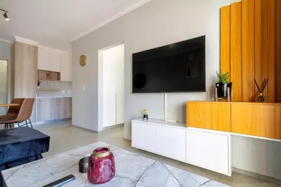 a living room with a television on a white cabinet at #AlimamaSpaces Thando's Waterfalls Villa in Midrand