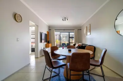 a dining room with a table and some chairs at #AlimamaSpaces Thando's Waterfalls Villa in Midrand