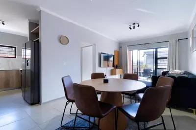 a dining room and living room with a table and chairs at #AlimamaSpaces Thando's Waterfalls Villa in Midrand