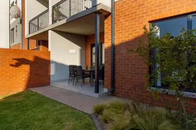 a patio with a table and chairs on a brick building at #AlimamaSpaces Thando's Waterfalls Villa in Midrand