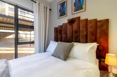 a bedroom with a white bed with a large window at #AlimamaSpaces Thando's Waterfalls Villa in Midrand