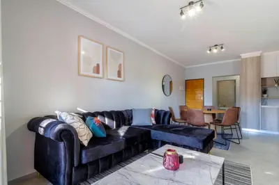 a living room with a couch and a table at #AlimamaSpaces Thando's Waterfalls Villa in Midrand