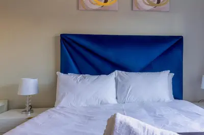 a bed with a blue headboard and white pillows at #AlimamaSpaces The Manson Umthunzi View in Vosburg