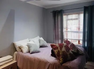 a bedroom with a bed with pillows and a window at The Chardonnay Inn in Centurion