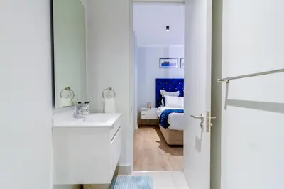 a white bathroom with a sink and a bed at #AlimamaSpaces The Chelsea's Cassini Ellipse in Vosburg
