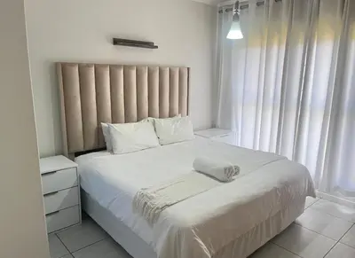 a bedroom with a white bed with a white pillow on it at Upmarket Luxury 1 bedroom Apartment in Kyalami