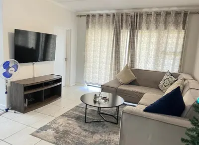a living room with a couch and a tv at Upmarket Luxury 1 bedroom Apartment in Kyalami