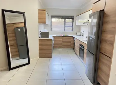 a kitchen with wooden cabinets and a stainless steel refrigerator at Upmarket Luxury 1 bedroom Apartment in Kyalami