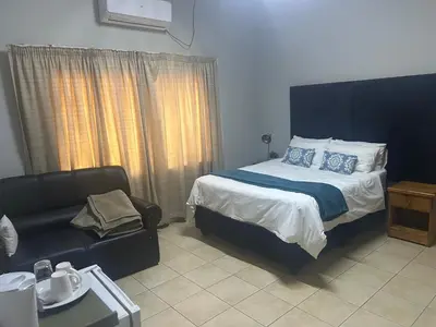 a bedroom with a bed and a couch at C'est Si Bon Accommodation at 53 Van Heerden Mokopane in Mokopane