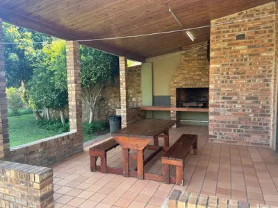 a patio with a table and benches on a brick wall at C'est Si Bon Accommodation at 53 Van Heerden Mokopane in Mokopane