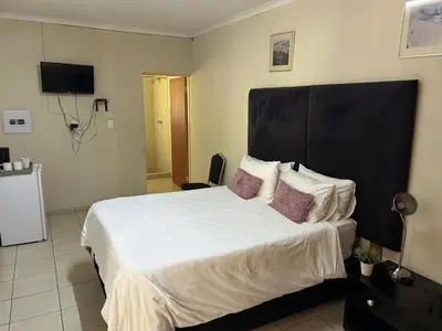 a bedroom with a bed with white sheets and purple pillows at C'est Si Bon Accommodation at 53 Van Heerden Mokopane in Mokopane