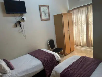 a hotel room with two beds and a tv at C'est Si Bon Accommodation at 53 Van Heerden Mokopane in Mokopane