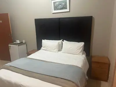 a bed with a black headboard and white sheets and pillows at C'est Si Bon Accommodation at 53 Van Heerden Mokopane in Mokopane