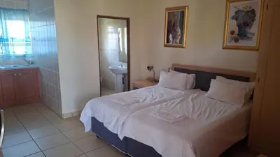 a bedroom with a bed and a bathroom with a sink at C'est Si Bon Accommodation at 03 Beitel, Mokopane in Mokopane