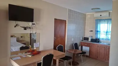 a room with a kitchen and a table with chairs at C'est Si Bon Accommodation at 03 Beitel, Mokopane in Mokopane